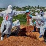 alt="Health workers in protective suits treating Ebola patients in Congo"