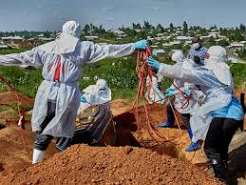 alt="Health workers in protective suits treating Ebola patients in Congo"